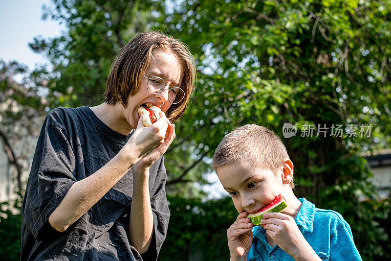 庆祝家庭团聚:性别不一致的青少年和弟弟分享美味的后院大餐