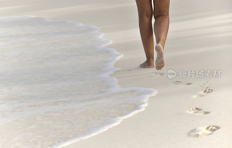 赤脚走在沙滩上的女人留下了脚印