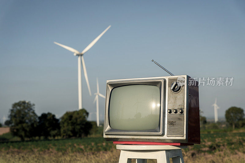 旧的复古电视与空白屏幕在板凳上的一个领域的风力涡轮机，背景
