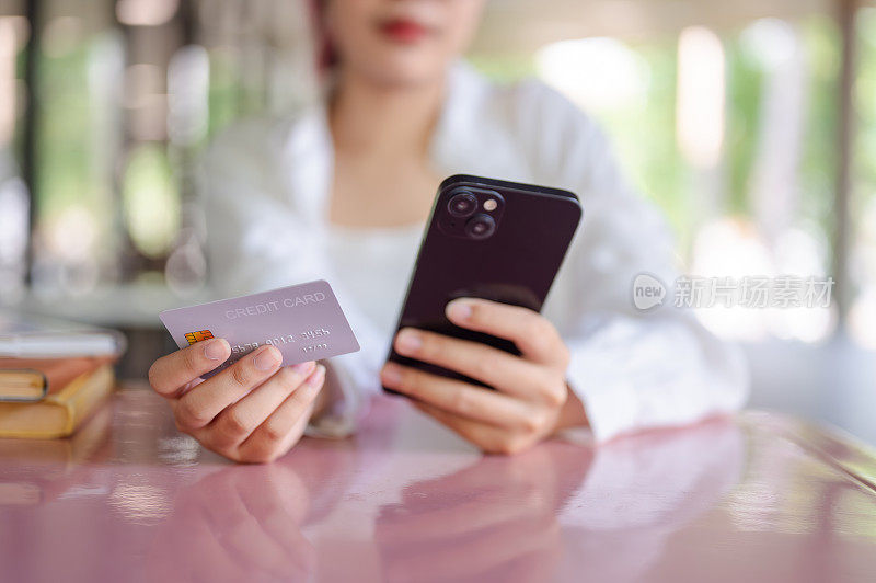 一名女性坐在自助餐厅的桌旁，正在使用手机银行应用程序。