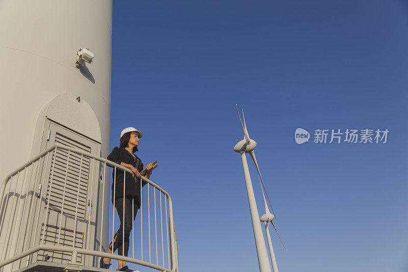 女商人正在用数码平板电脑检查风力涡轮机的可再生能源。