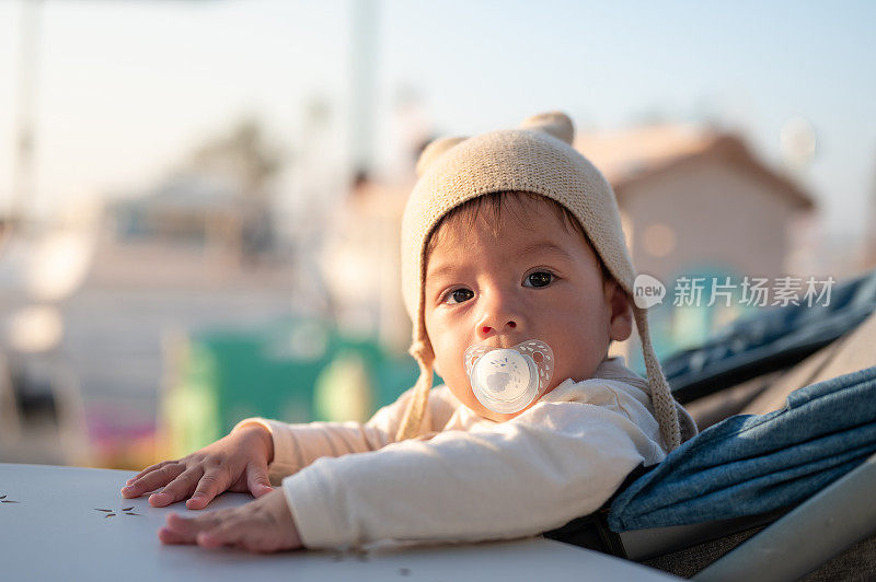 小男孩坐在户外的咖啡吧里，靠在桌子上