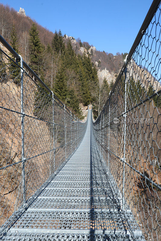 吊桥由坚固的钢索和金属枕木组成，连接山谷的两端