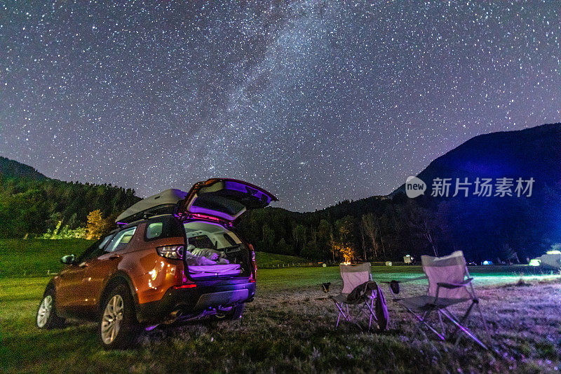 露营椅和汽车在山上美丽的银河天空下