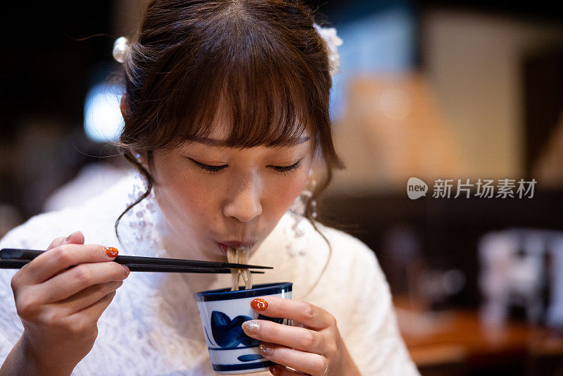 身着白色蕾丝和服的女子在日本餐厅吃荞麦面午餐