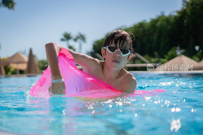 戴着泳镜的快乐男孩在游泳池放暑假