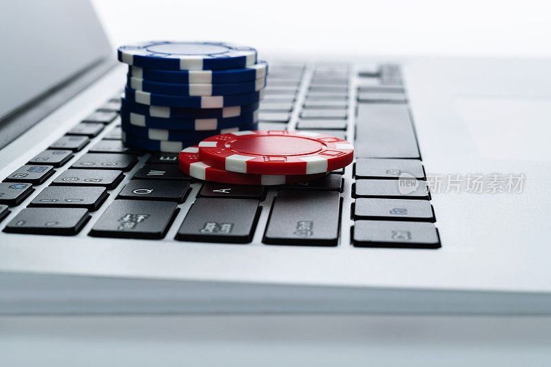 笔记本电脑键盘与赌博筹码在白色背景