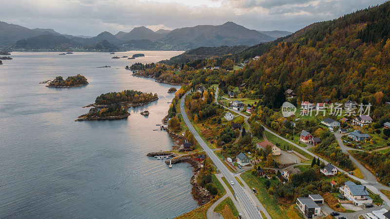 航拍的汽车行驶在海上的道路与风景秀丽的山和岛在日落时在挪威