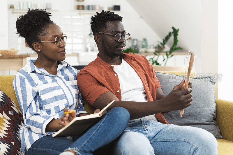 快乐的非洲裔夫妇阅读食谱，选择烘焙什么