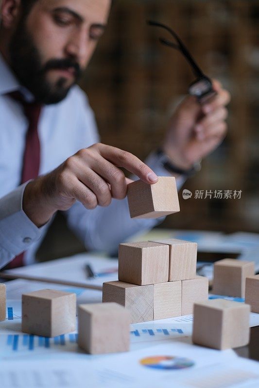 商人通过用木块建造高楼来展示增长战略