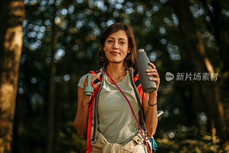 一个有吸引力的女徒步旅行者喝水的肖像