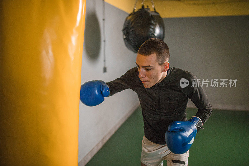 一个年轻的自由搏击运动员在拳击馆训练，专注于变得更强壮