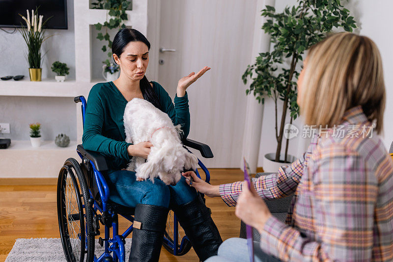 坐在轮椅上的年轻女子通过她的治疗犬和心理治疗师的治疗找到了安慰和联系