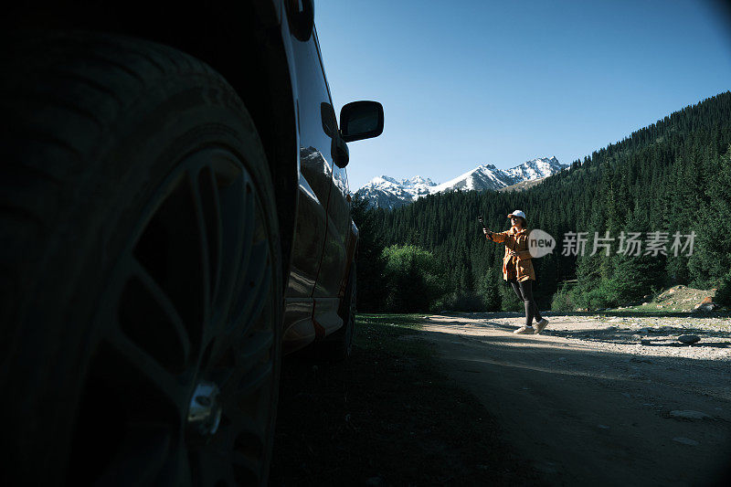 一名女游客在自驾游中拍摄雪峰