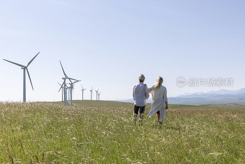一对夫妇在风力涡轮机下的草地上放松