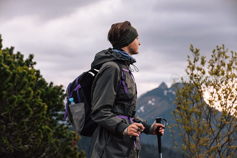 女人的女性肖像，谁在山中旅行。穿着保暖运动服在户外徒步旅行的人。生活方式摄影的人物和北欧徒步，旅游的概念。女孩是背包客，背包里装着旅游装备。