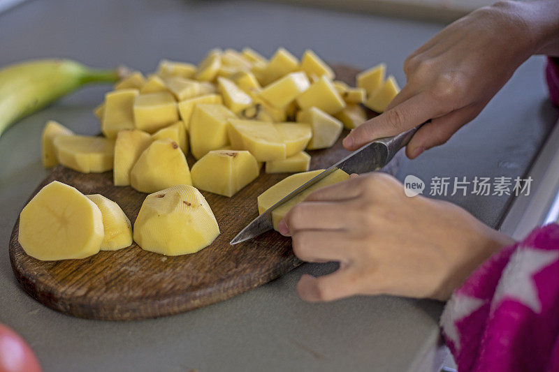 在砧板上用刀把土豆切成小块。flatlay
