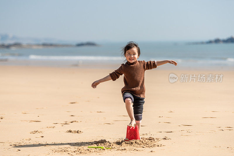 一个中国小女孩在沙滩上玩沙子