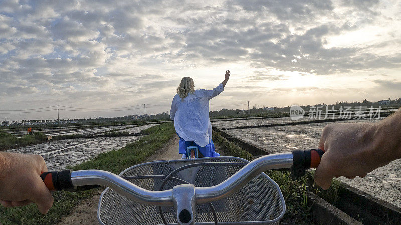 成熟的夫妇骑着自行车穿过稻田