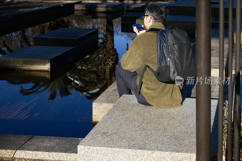 成年男子在户外用智能手机通话的后视图