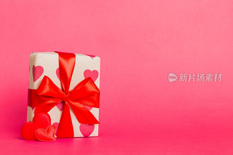 礼盒与红色蝴蝶结和红色的心在彩色背景。透视图。平躺