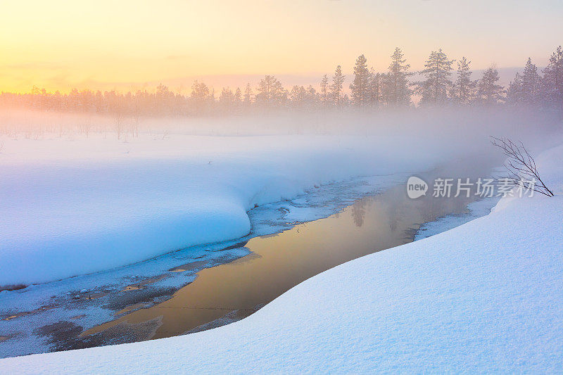 色彩缤纷的冬季日落在森林和河流与美丽的薄雾