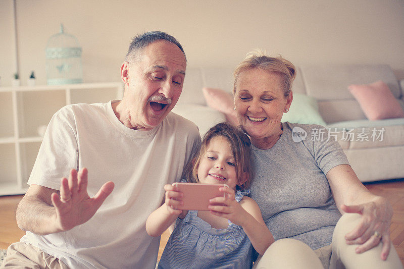 奶奶和爷爷和他们的孙女使用智能手机。