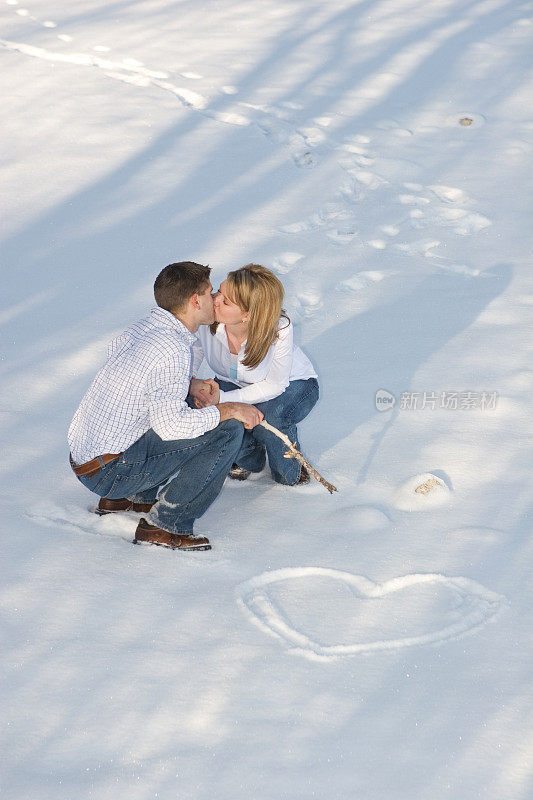 情侣在心形的雪中接吻