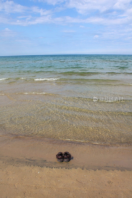 沙滩上一双凉鞋，海浪从上面流过。