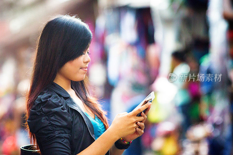 年轻的印尼妇女在街头市场发送短信简介