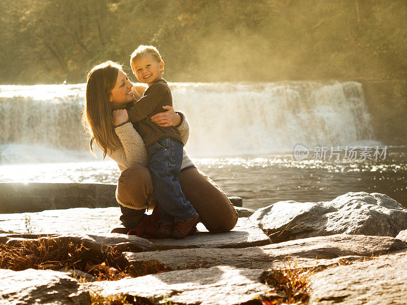 母亲抱着瀑布旁的儿子