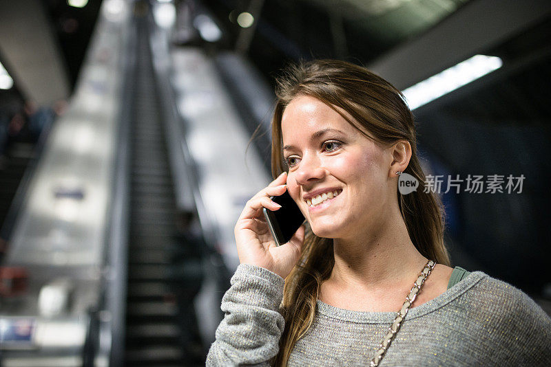 一个女人在地铁站里用智能手机
