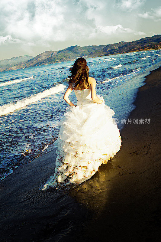 一个新娘，穿着婚纱在海浪边奔跑
