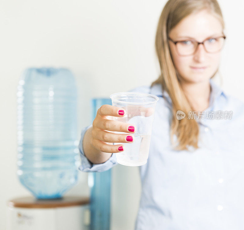 女商人用饮水机喝水。