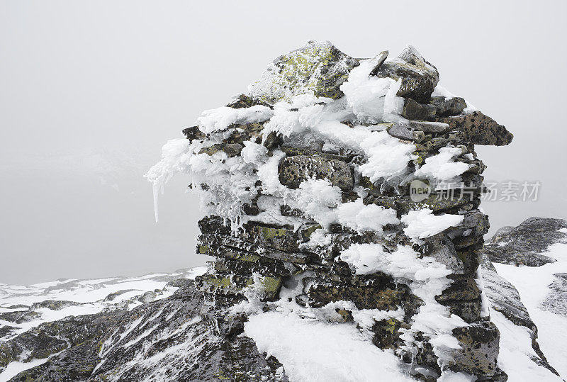 结霜的石冢标志着山的顶峰在冬天的雾