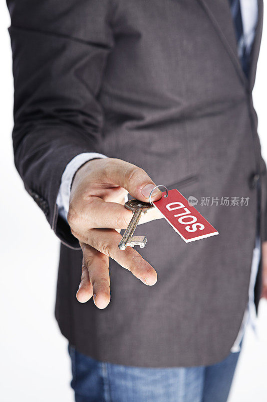 房地产经纪人举着红色卖出标志的旧钥匙