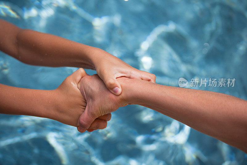 一双从水中救出另一个人的手。