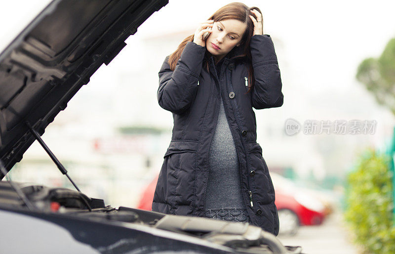 一个孕妇站在一辆破车旁