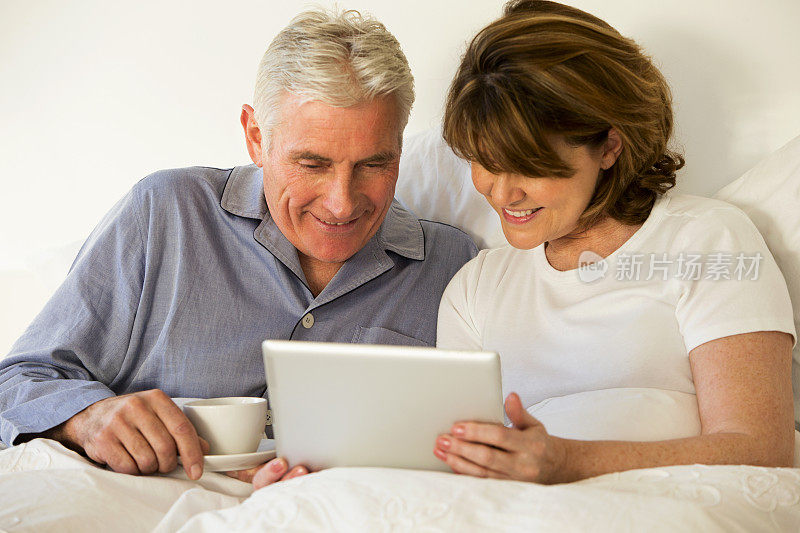 一对老年夫妇在床上使用笔记本电脑