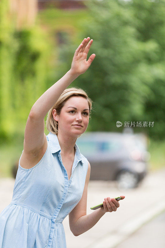 年轻女子拿着手机找出租车