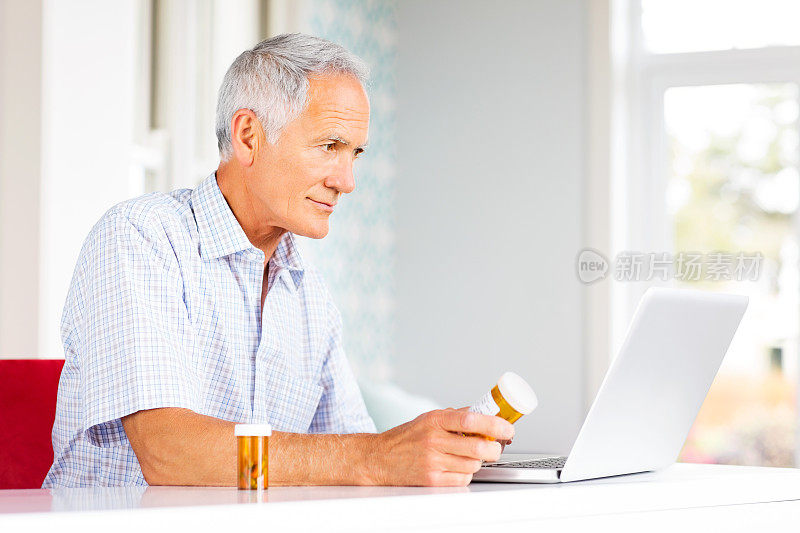 使用笔记本电脑使用药瓶的老年人。