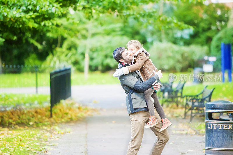 父亲抱着女儿在伦敦的公园里