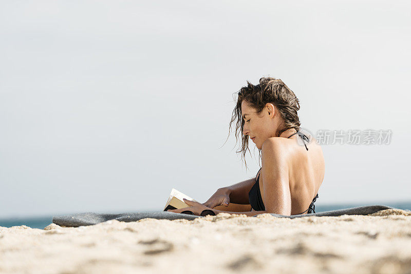 年轻女子在康沃尔的波斯科诺海滩晒太阳。