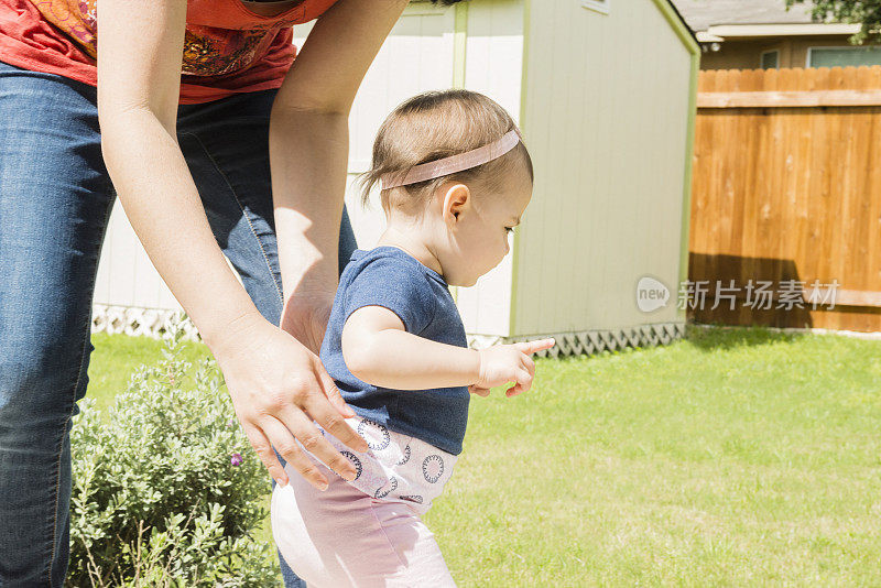 母亲和婴儿在美国后院学习走路