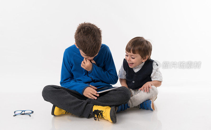 休闲儿童坐在地板上使用数字平板电脑