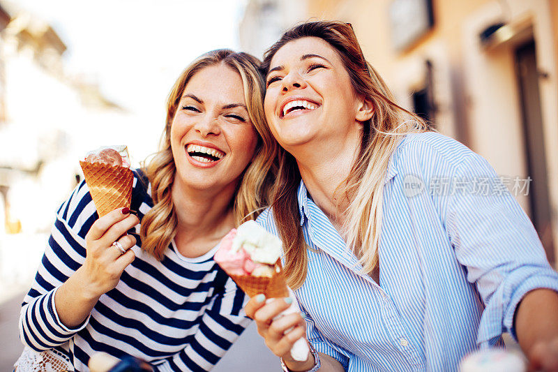 两个年轻的女人笑着手里拿着冰淇淋