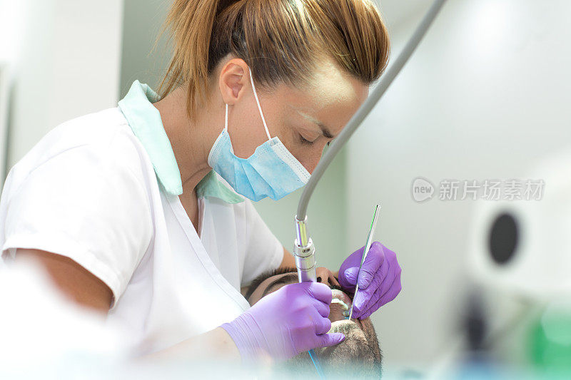 女牙医在牙医的椅子上检查男人的牙齿