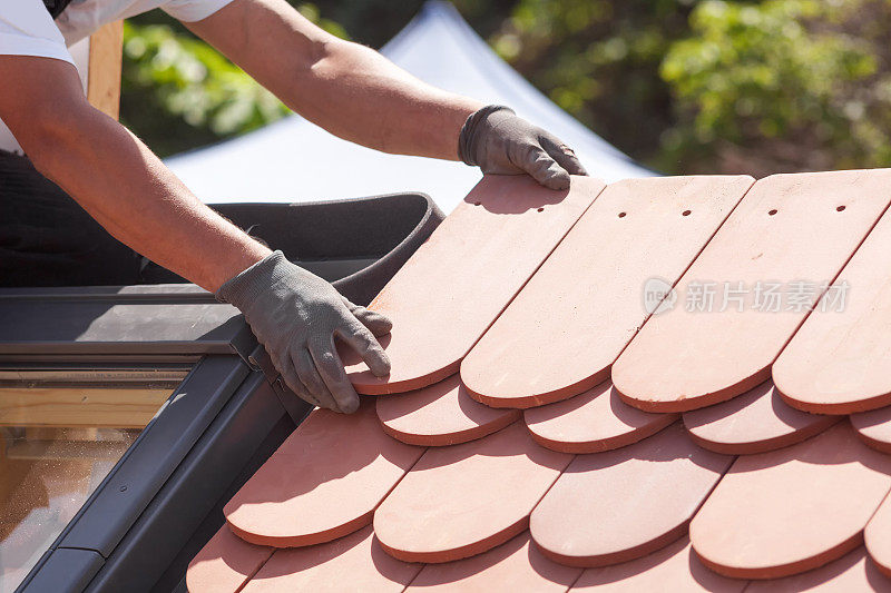 屋顶工人在屋顶上铺设瓦片。安装天然红瓷砖。