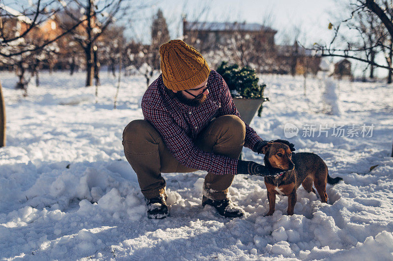 下雪天的户外，一个带着狗的大胡子男人