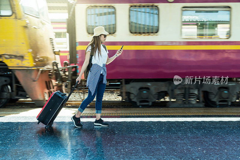 亚洲女人旅行者走和拖行李的运动模糊了火车运行在火车站，旅游和生活方式的概念